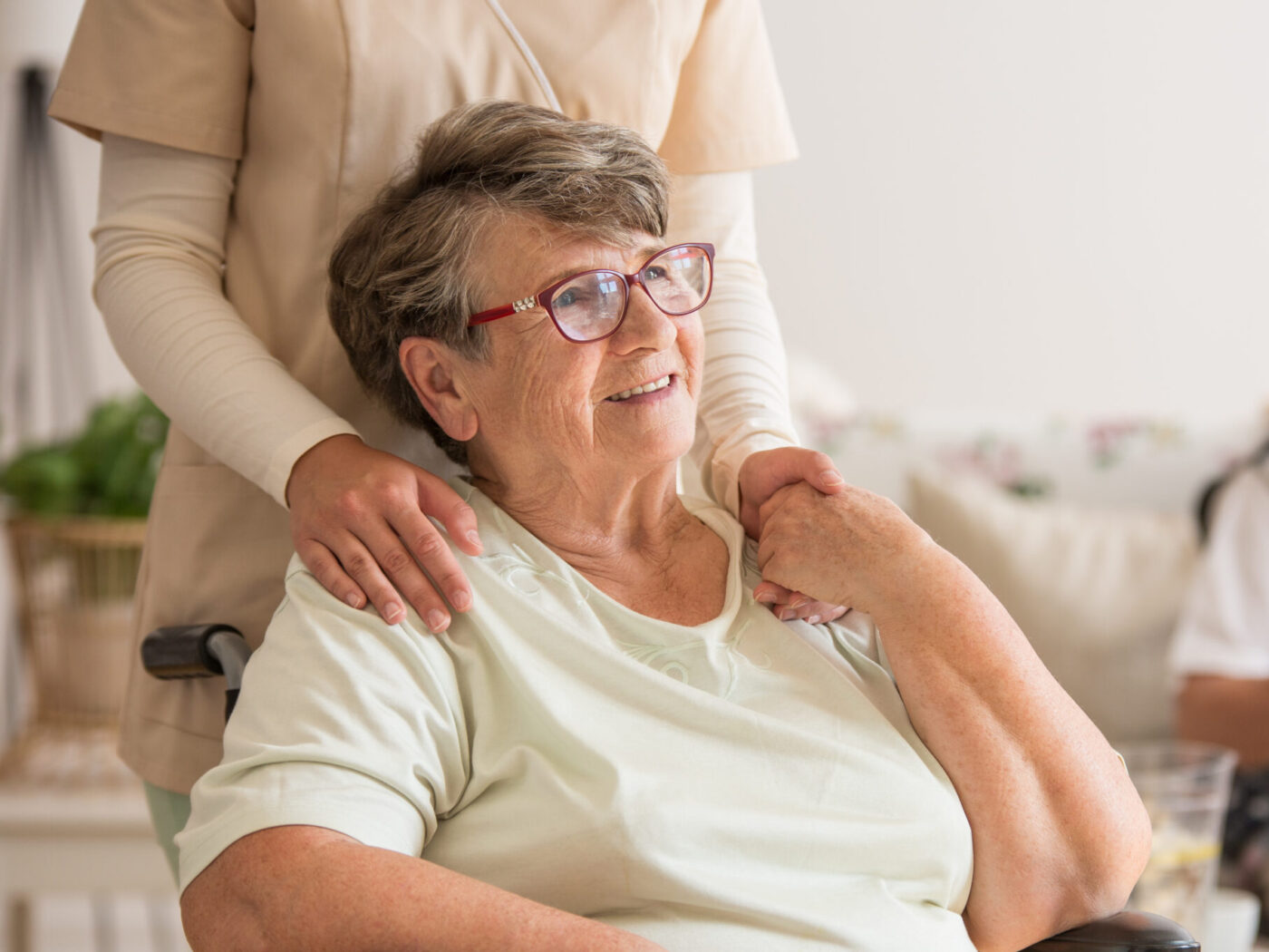 Woman in a wheelchair being comforted by a carer