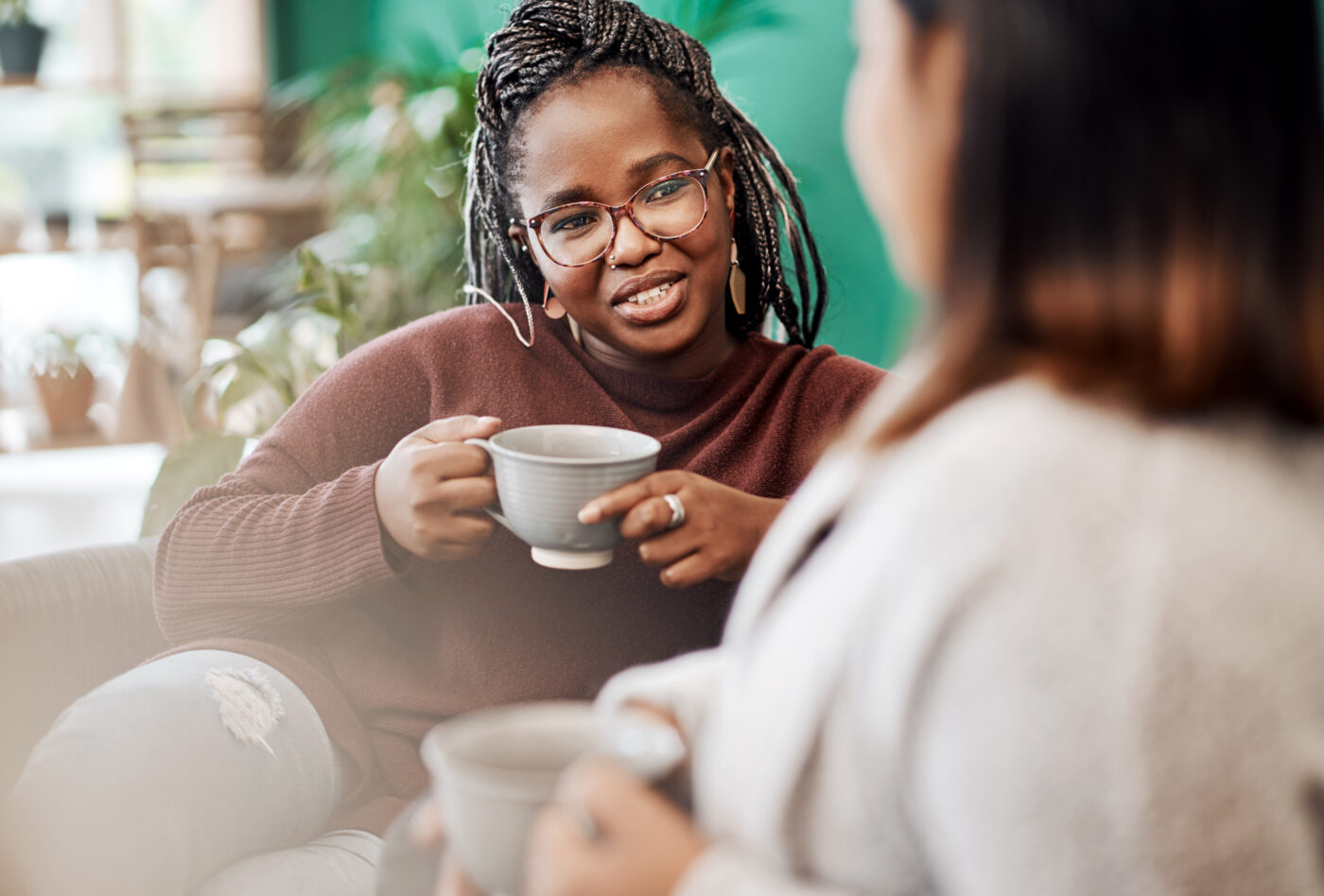 Two women sitting on a sofa having coffee together
