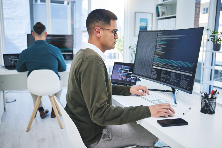 Software developer sitting at a desk using a large computer screen