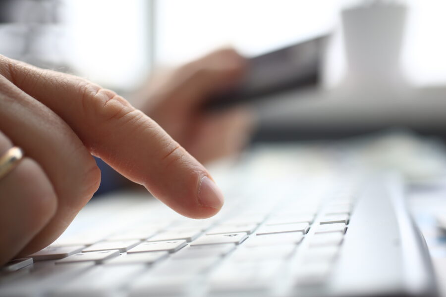 Male arms in suit typing on silver keyboard using computer pc at office workplace closeup. Accountant finger job modern lifestyle web search assistant enter account login password and note credential
