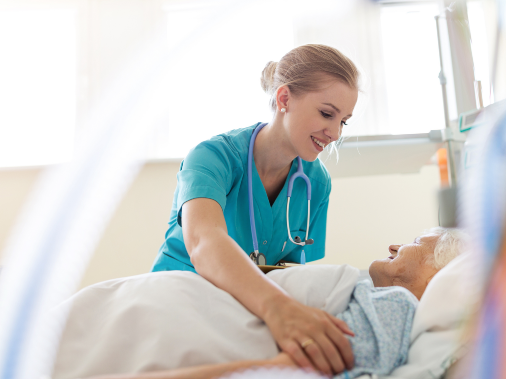 Clinician attends to elderly patient in hospital bed